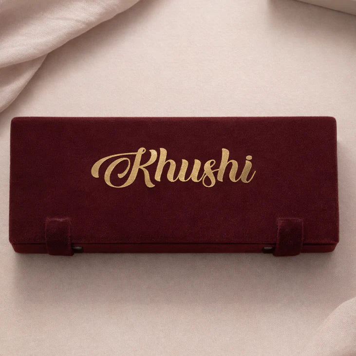 Maroon jewelry box with 'Rhushi' branding on a beige background