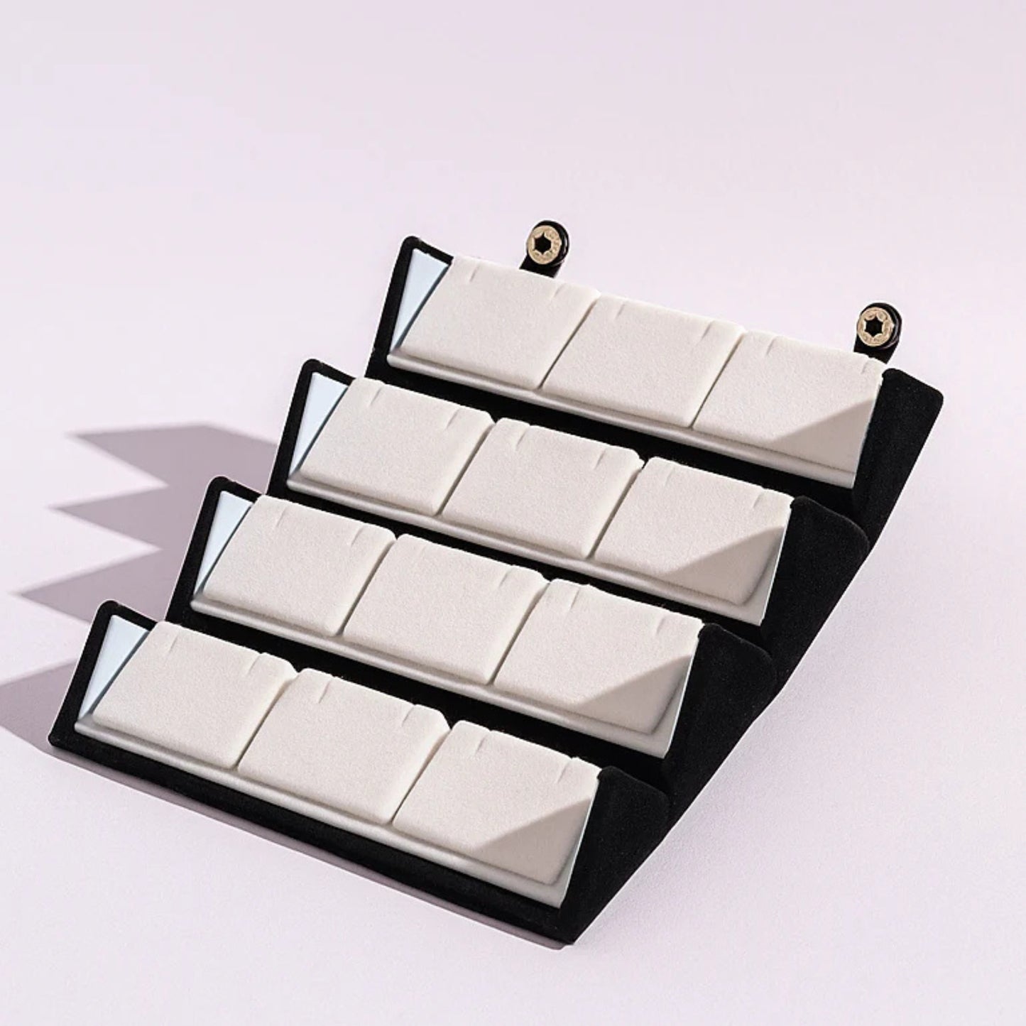 Set of white geometric blocks in a black display case on a light purple background