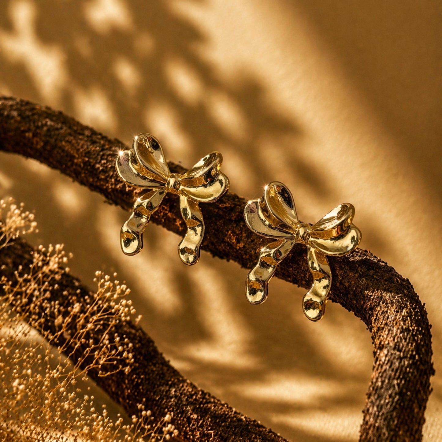 Gold bow-shaped earrings on a textured brown surface with a warm glow.